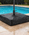 Patio Umbrella Base Cover For Square Stands Heavy Duty 600D Waterproof Anti UV Weatherproof Cover Only 30 Inch By 30 Inch By 5 Inch Black Fits Most Square Bases protecting against rain by a poolside.