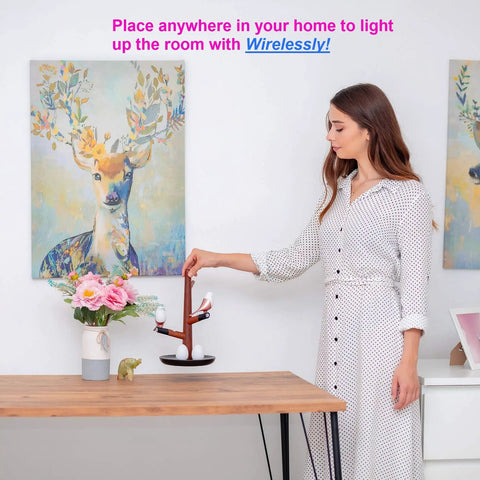 Woman placing Tree Of Lyte Motion Sensor Bird Night Light Dimmable Wireless Rechargeable Modern Desk Rose Gold Wood Lamp on table.