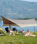 Camping setup with Must Have All Weather 12x14 Foot Waterproof Camping Tarp With Two Poles Sun Shelter by a lakeside