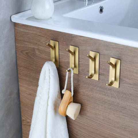 Brushed Gold Self Adhesive Wall Hooks Four Pack Stainless Steel Towel Coat Hat Robe Hangers For Bathroom And Kitchen No Drill Easy Install Rustproof Strong Hold In Wet Environments on wooden surface