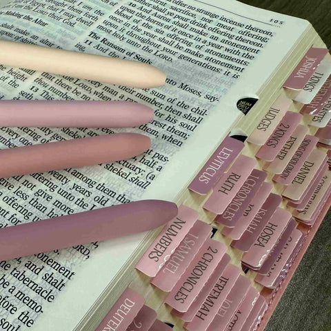Pink Gel Pens 7 Pack 0.5mm Fine Point Quick Dry Black Ink Smooth Writing For Journaling Notes And Classwork next to a tabbed book
