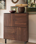 Wooden cabinet with four doors featuring metal handles, decorated with a lamp and artwork in a classic living room setting.