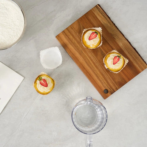 Flat lay of Greaseproof Cupcake Liners 4000 Pack, 4 Oz Disposable Muffin Cups on a wooden board, some filled with cupcakes.