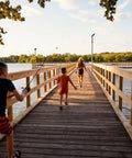 Children playing on a dock, one holding a Kids Fishing Rod And Reel Combo, 29 Inch Floatable Spincast Set With 20 Size Reel.