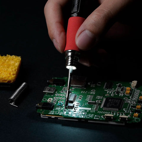Hand using TS21 Pro Grade Soldering Iron Kit With Adjustable Temperature USB Type C Power Station Digital OLED Display for circuit board soldering.