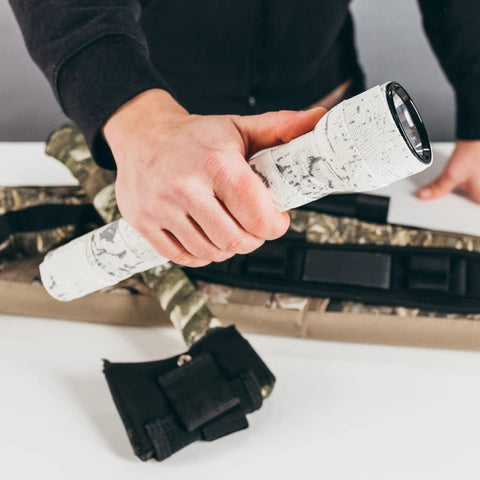 Hand holding flashlight wrapped in Self Cling Camouflage Fabric Wrap For Gear And Knives, Reusable And Washable, 2 Inch By 144 Inch