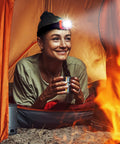 Camper wearing Rechargeable LED Headlamp With Wave Sensor Two Pack Ultra Bright 1000 Lumens in tent by fire, smiling.