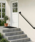 Heavy Duty Four Foot Iron Stair Handrail In Matte Black Finish Rust Resistant Body For Indoor Or Outdoor Staircases With Dead Simple Hardware Setup For Quick Weekend Fixes installed on steps leading to a white door.