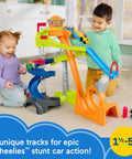 Toddlers playing with Hot Wheels Spiral Stunt Speedway Race Track Playset with loop and jump features.