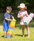 Children holding Giddy Buggy Kid-Sized Folding Lawn And Camping Chair with Cup Holder, water-resistant fabric, in outdoor setting