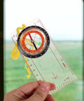 Multifunctional Survival Compass With Measuring Scale And Beefed Up Buckle for outdoor navigation, held in hand