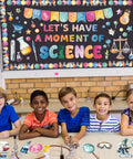 Children in front of bulletin board with Science Bulletin Board Set For Classroom Decor 89 Pcs including colorful scientific cutouts.