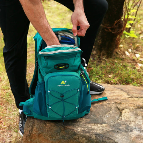 Person reaching into Hydration Backpack With 3L Water Bladder, 18L Multipurpose Hiking Pack For Outdoors resting on a rock