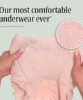 Hands showing textured material of Fresh Protection Adult Incontinence Underwear For Women Large 28 Count Disposable Maximum Absorbency Blush.