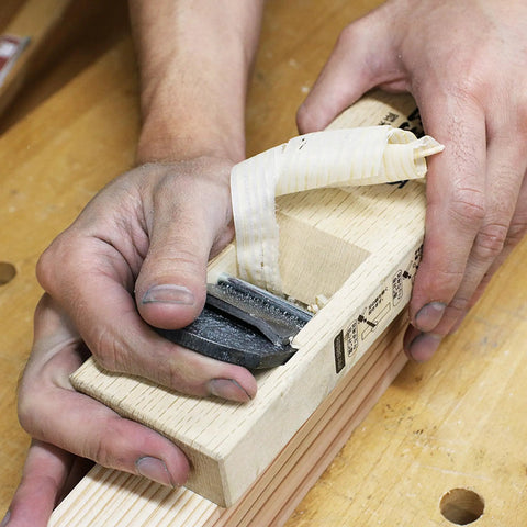 Hand using Pro Grade Japanese Kanna Pull Plane Hitachi Aogami Blue Steel Number Two Blade Solid Oak Body 58mm for woodworking.