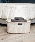 40L Laundry Basket With Lightweight Build And Premium Wicker Look Ivory Plastic Hamper in bedroom next to bed