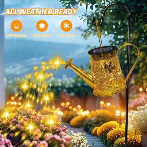 Golden solar hummingbird watering can lantern lights with rain shower effect in a garden, weatherproof, outdoor garden decor.