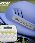 Top Shelf Monochrome Label Maker With No Brainer Setup And Dozen Smart Templates For Fast Home Office Organization printing name labels on a blue hard hat.