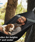 Man relaxing with dog in Uniki Hammock Stand With 3 Year Warranty Instant 30 Second Foldable Hammock Setup 550 Lb Capacity For One Person Grab And Go Portable Durable Outdoor Indoor Use Black Perfect For Camping Backyard Patio And Cozy Lounging