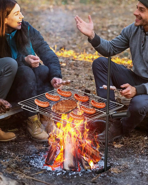 People grilling sausages on Portable Campfire Grill Grate For Fire Pit Foldable Stainless Steel With Height Adjustable Legs