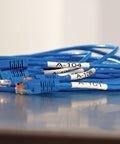 Heavy Duty Industrial Heat Shrink Label Rolls, 1/4 Inch Tube With Black Print On White labels on blue network cables.
