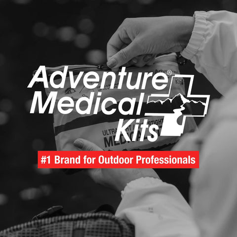 Hands holding Ultralight Watertight Medical Kit.9 from Adventure Medical Kits, outdoors.
