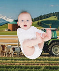Baby in a onesie against a farm backdrop, featuring cows, a tractor, and a barn with mountains.