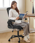 Woman sitting on an ergonomic office chair with adjustable lumbar support and breathable mesh flip up armrests, black color.