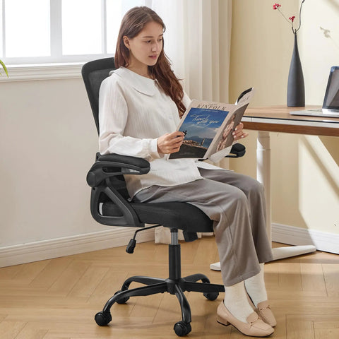 Woman sitting on an ergonomic office chair with adjustable lumbar support and breathable mesh flip up armrests, black color.