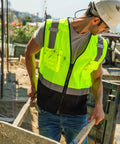Boss Level Hi Vis Reflective Safety Vest Built Different To Keep You On Point All Shift Long With Durable Zipper Closure And Smart Black Bottom Mesh Panels For Road Work Projects, worn by a worker handling materials.