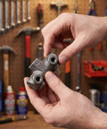 Person holding Built Tough Cast Iron Air Compressor Four Way Manifold Block With One Half Inch And One Quarter Inch Female Threads