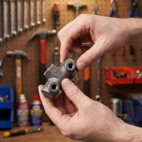 Person holding Built Tough Cast Iron Air Compressor Four Way Manifold Block With One Half Inch And One Quarter Inch Female Threads