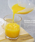 Elite Gourmet Compact Electric Citrus Juicer In White 30 Watt With 16 Oz Capacity for fresh orange juice pouring into a glass.