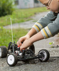 Child adjusting a remote-controlled car outdoors on a sunny day, engaging in a DIY model-making project.