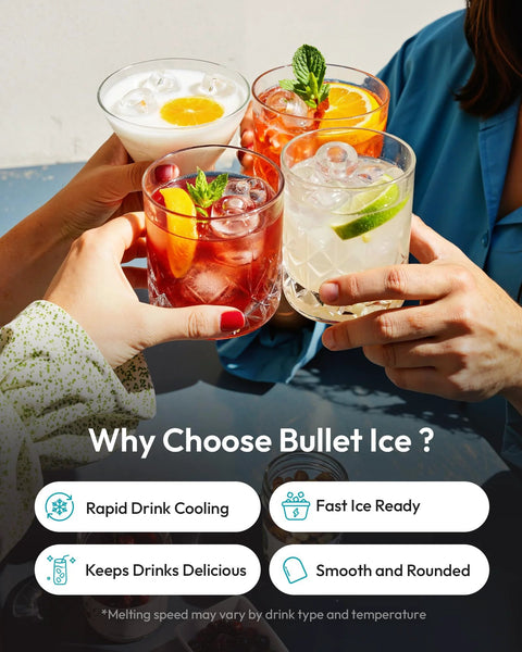 Group of people toasting with ice-filled cocktails in clear glasses on a table.