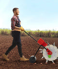 Person using manual hand push garden seeder walk behind row crop planter with 10 nozzles in a field.
