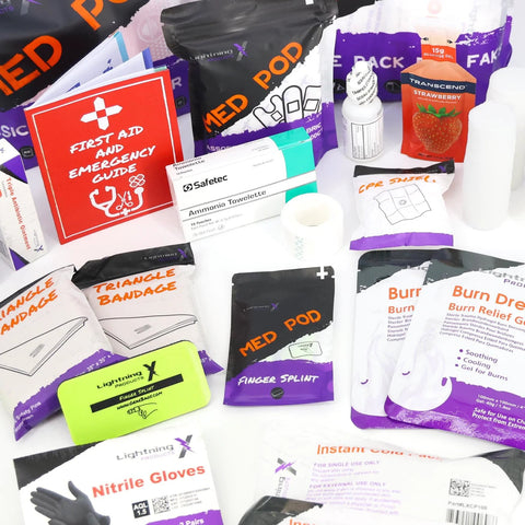 Lightning X first aid supplies assortment with gloves, towelettes, burn gel, dressings, and a red First Aid guide.