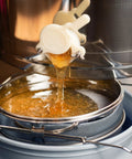 Honey flowing through stainless steel honey strainer with dual sieve for beekeeping, fine and coarse mesh filter to harvest pure honey