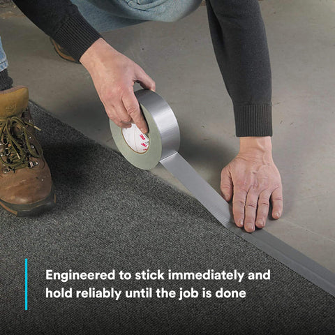 Person applying Extra Heavy Duty Duct Tape 6969, Silver, Industrial Strength, tearing with hand on carpet seam