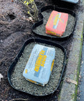 Made In USA Set Of Flexible Custom Stepping Stone Molds For Concrete And Garden Paths filled with gravel, bags of Quikrete on top.