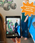 Child using Grave Digger Monster Jam wall decal with 3D augmented reality interaction in bedroom, tablet shows AR character.