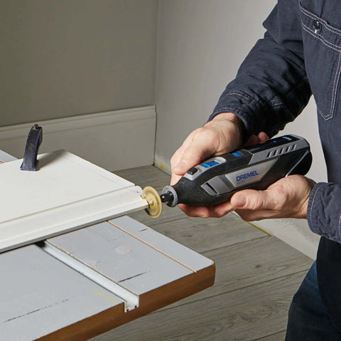 Dremel 8250-5 cordless rotary tool with sanding wheel attached, blue/black body, in use on wood.