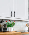 Matte Black 25 Pack Cabinet Handles 3 Inch Hole Centers installed on white kitchen cabinet doors, showcasing modern design.
