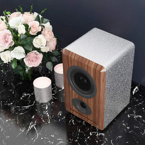 Speaker on table with candles and flowers, partially covered with Easy Peel And Stick Glitter Wallpaper For Walls And Surfaces.