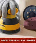 Hand holding a DeWalt sander with 52 Piece Sander Pad And Discs Combo Kit With 2 Pack 5 Inch 8 Hole Hook And Loop Pads And 50 Sanding Discs.