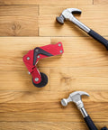 Thinking Process: red aluminum motorcycle chain adjuster with roller wheel beside two hammers on wood floor