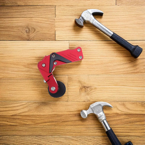 Thinking Process: red aluminum motorcycle chain adjuster with roller wheel beside two hammers on wood floor