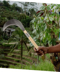 Long Handled Mowing Knife Garden Hoe With Wooden Handle held outdoors for weeding and harvesting