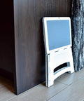Grab And Go Ultra Compact Mini Folding Step Stool Lightweight 2.5 Lb design leaning against wall, collapses under 1 inch, white.