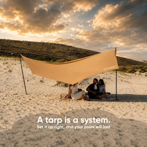 Beach setup with Adjustable Aluminum Telescoping Tarp Poles For Tarps Canopies And Awnings, providing shade on sandy terrain.